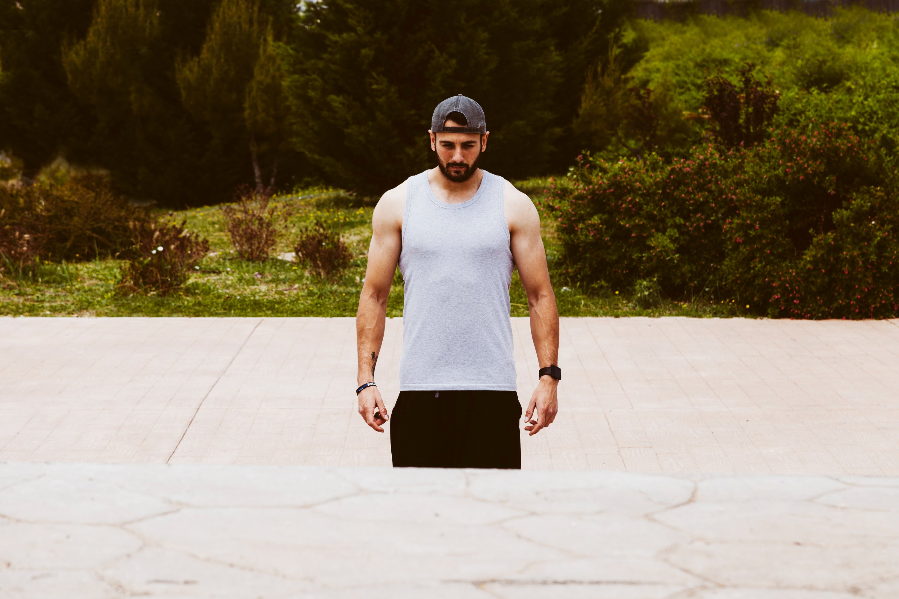 A man is standing, wearing a tank top.